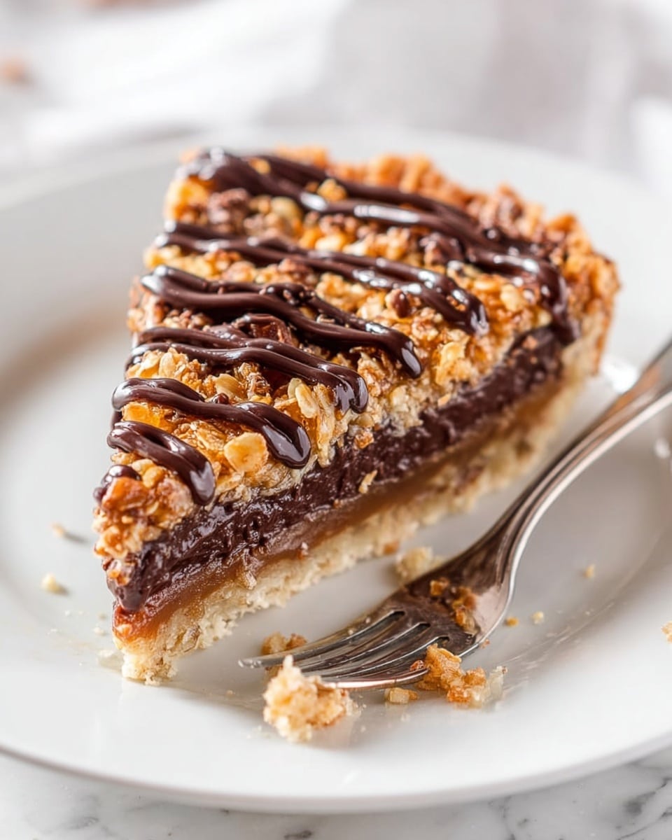 A slice of pie placed on a white plate on a white marbled surface. The pie has three visible layers: the bottom layer is a light beige crumbly crust, the middle layer is a thick, dark brown, smooth chocolate filling, and the top layer is a textured mix of golden brown nuts or oats coated in a glossy syrup. On top, there are three thick swirls of dark chocolate drizzled across the slice. A shiny silver fork is placed near the slice, with some crumbs scattered around on the plate. Photo taken with an iphone --ar 4:5 --v 7