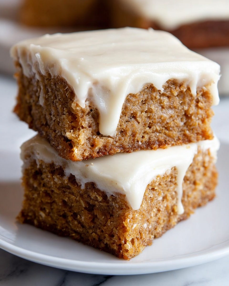 The image shows two square pieces of cake stacked on a white plate, set on a white marbled surface. Each cake has two layers: a thick bottom layer that looks moist and crumbly with a brown color and visible texture, and a smooth, creamy white frosting layer on top that slightly drips down the sides. The top piece of cake clearly shows the soft cake layer with frosting on top, while the bottom piece is partially hidden but visible enough to display the same two-layer structure. The lighting highlights the texture of the cake and the smoothness of the frosting, creating a fresh and inviting look. photo taken with an iphone --ar 4:5 --v 7