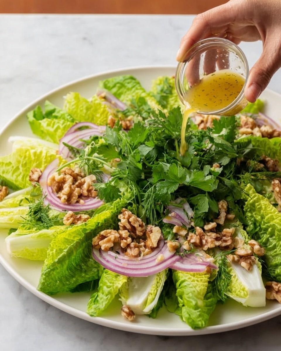 A large white plate holds a fresh green salad made of crisp romaine lettuce leaves arranged as the first layer, topped with thin slices of red onions and a generous amount of chopped walnuts scattered across. On top of the salad, there are fresh green herbs, possibly parsley. A woman's hand is adding leaves of fresh herbs while another woman's hand pours a golden dressing over the salad from a small clear container. The background is a white marbled surface. photo taken with an iphone --ar 4:5 --v 7