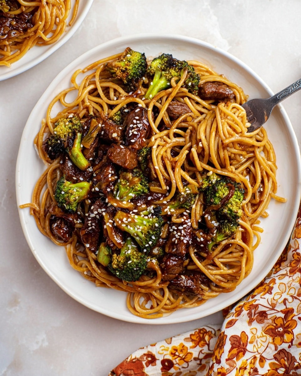 The image shows a large black wok filled with stir-fried noodles that are golden brown and glossy from sauce. Mixed through the noodles are many pieces of cooked beef, dark brown with a slightly caramelized surface, cut into medium strips and chunks. Scattered around are small, bright green broccoli florets that add a splash of color. A black spatula is partially visible at the bottom right, stirring the noodles. The surface beneath the wok is white with a marbled texture, making the colors of the food stand out clearly. photo taken with an iphone --ar 4:5 --v 7