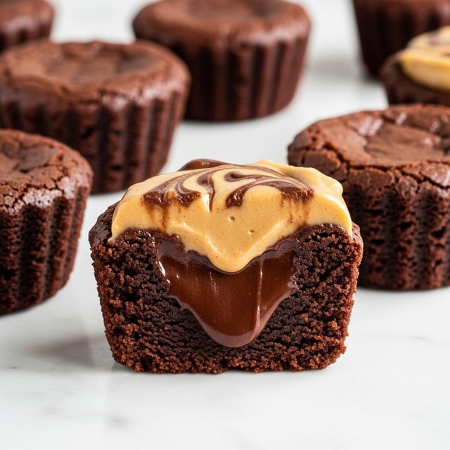 The image shows a close-up of several small chocolate brownies shaped like cups, placed on a white marbled surface. The front brownie is cut in half to reveal its layers: a dense, dark brown chocolate base and middle with a smooth, glossy, melting chocolate center, topped by a swirled layer of light brown creamy peanut butter that slightly drips over the edge. The edges of the brownies are slightly crumbly and textured, with rich chocolate tones, while the peanut butter layer adds contrast with its creamy, matte finish. The rest of the brownies in the background remain whole, showing a rough, cracked top surface. photo taken with an iphone --ar 4:5 --v 7