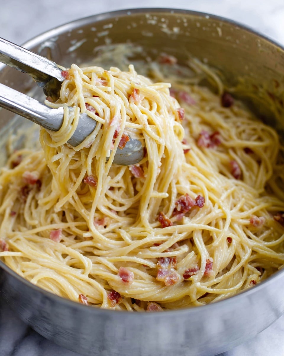 A white bowl holds a small, neat mound of creamy spaghetti that is light yellow in color with bits of browned bacon mixed in. The pasta looks smooth and glossy from the sauce coating each strand. On top, there is a generous layer of finely grated white cheese sprinkled evenly with some black pepper flakes. The bowl sits on a white marbled surface with a soft, out-of-focus background. photo taken with an iphone --ar 4:5 --v 7