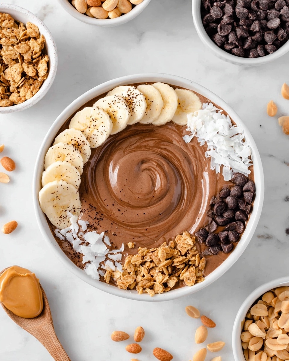 A white bowl filled with smooth, swirled brown chocolate smoothie in the center. Around the top edge inside the bowl, there are six sections of toppings: sliced light yellow banana with a dusting of black specks, bright white coconut flakes, light brown crunchy granola, small dark brown chocolate chips, light tan peanut butter in a creamy dollop, and salted peanuts in light beige. The bowl is set on a white marbled surface with other white bowls around containing similar ingredients such as chocolate chips, banana slices, peanut butter, and peanuts. A light colored wooden spoon is placed near the bowl. photo taken with an iphone --ar 4:5 --v 7